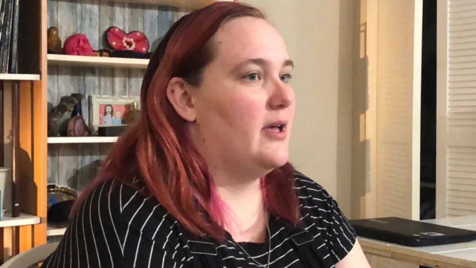 Une femme qui a les cheveux teints en rouge accorde une entrevue à la caméra.