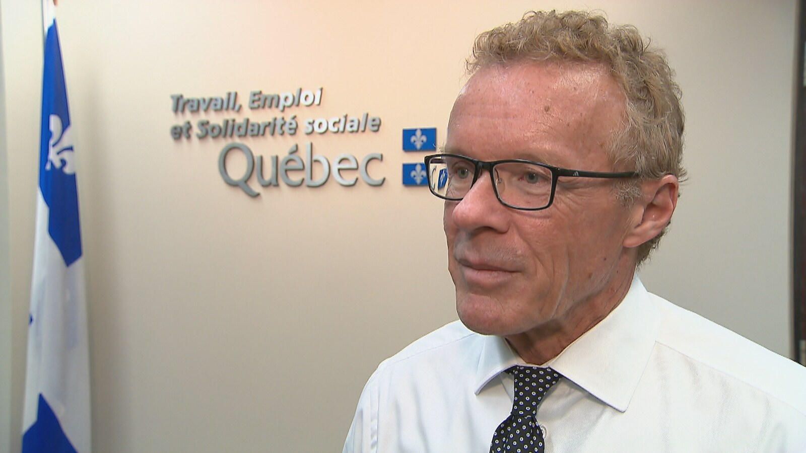 Le ministre Jean Boulet pose devant un drapeau du Québec.