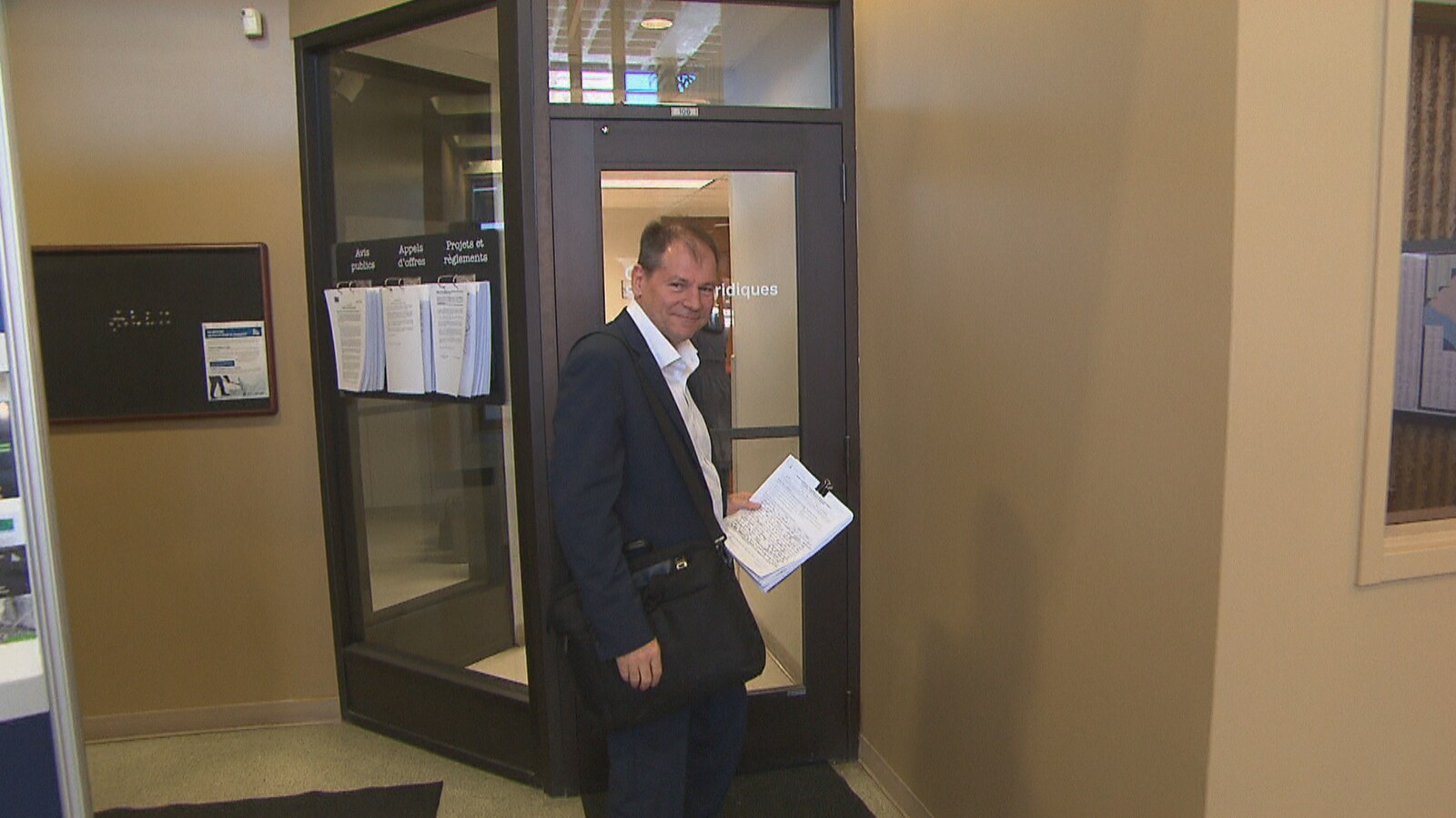 Jean-François Aubin tient des feuilles dans ses mains dans l'entrée de l'Hôtel de Ville.