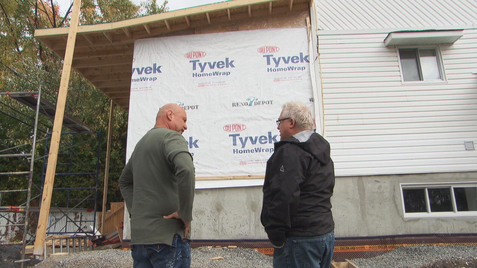 Mario Gauthier (à gauche) et le conseiller municipal Jean Lessard (à droite) devant un pan de maison en rénovation.