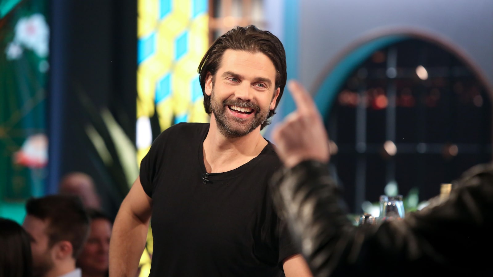 L'animateur sourit au milieu du plateau de tournage.