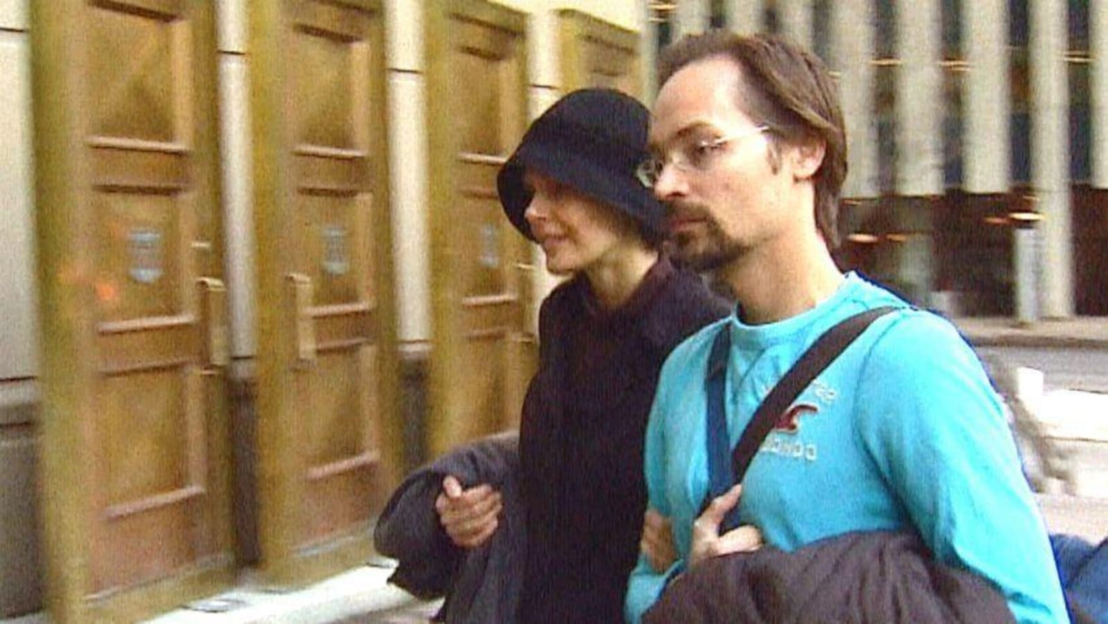 Jennifer Clark porte un manteau et un chapeau noir. Jeromie porte des lunettes et un chandail bleu. Ils se rendent à leur procès.