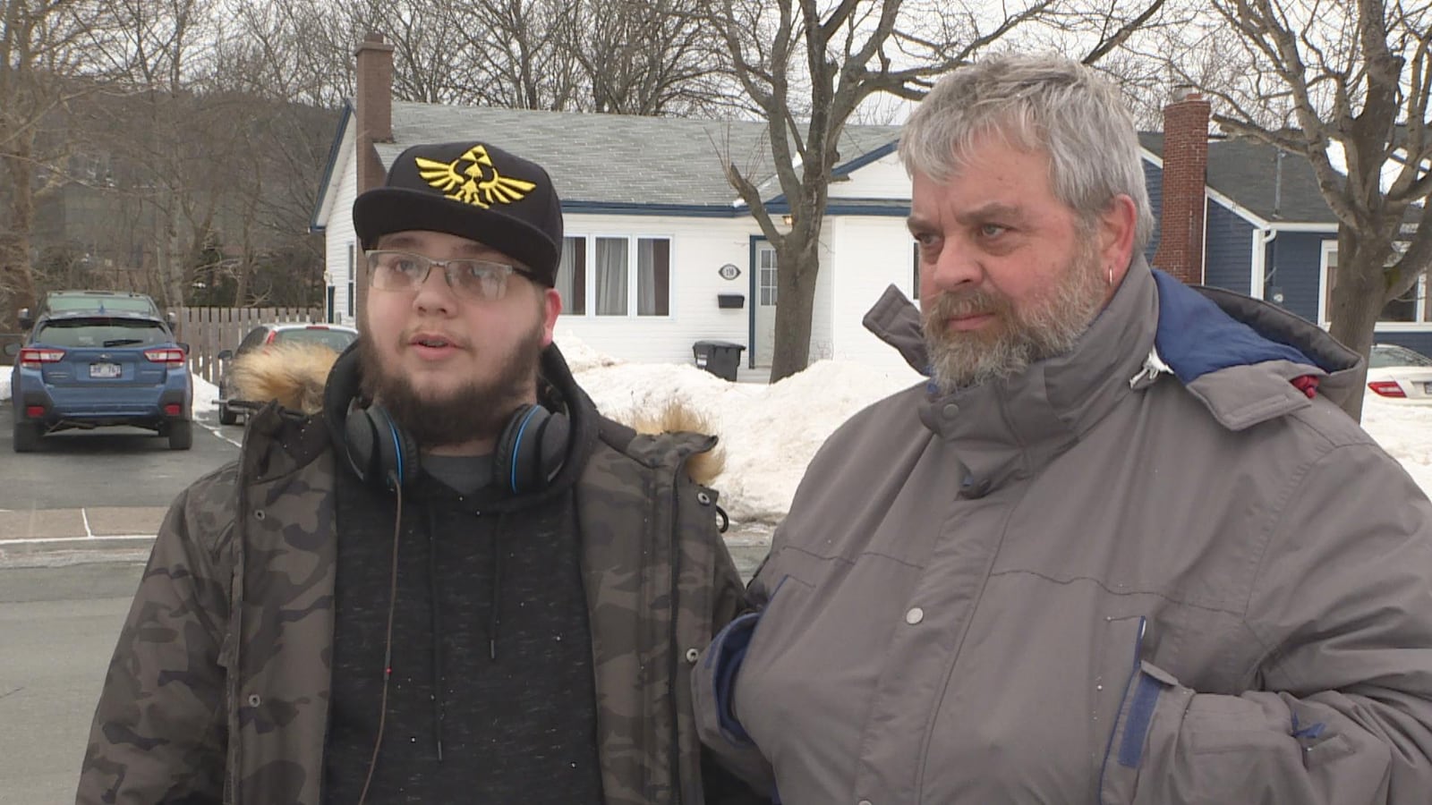 Portrait de Jessy Mahé et de son père, Denis Mahé, à l'extérieur devant des maisons.