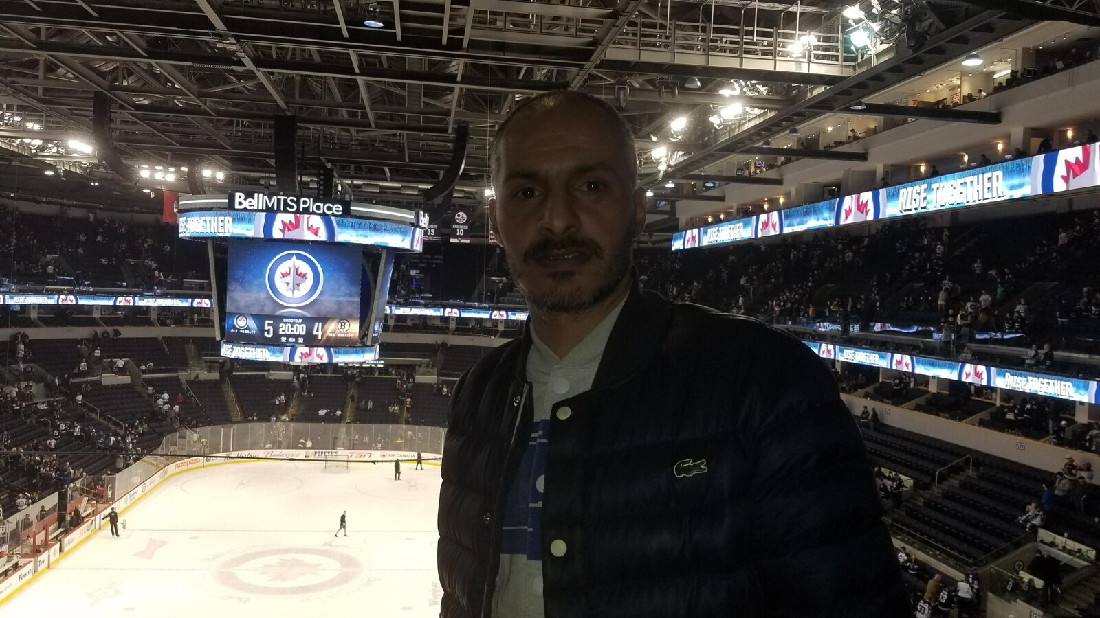 Un homme pose devant la glace d'une arena de hockey