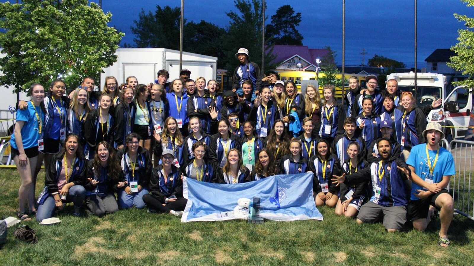 Une cinquantaine de jeunes assis, à genoux et debout posent pour l'objectif avec un drapeau franco-ténois en premier plan.