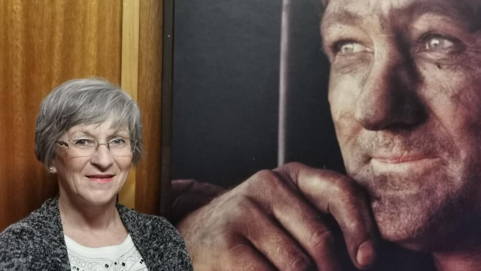 Joanne Sheppard, l'instigatrice du projet de parc commémoratif, pose devant une photo en format géant de son père, le visage noirci.