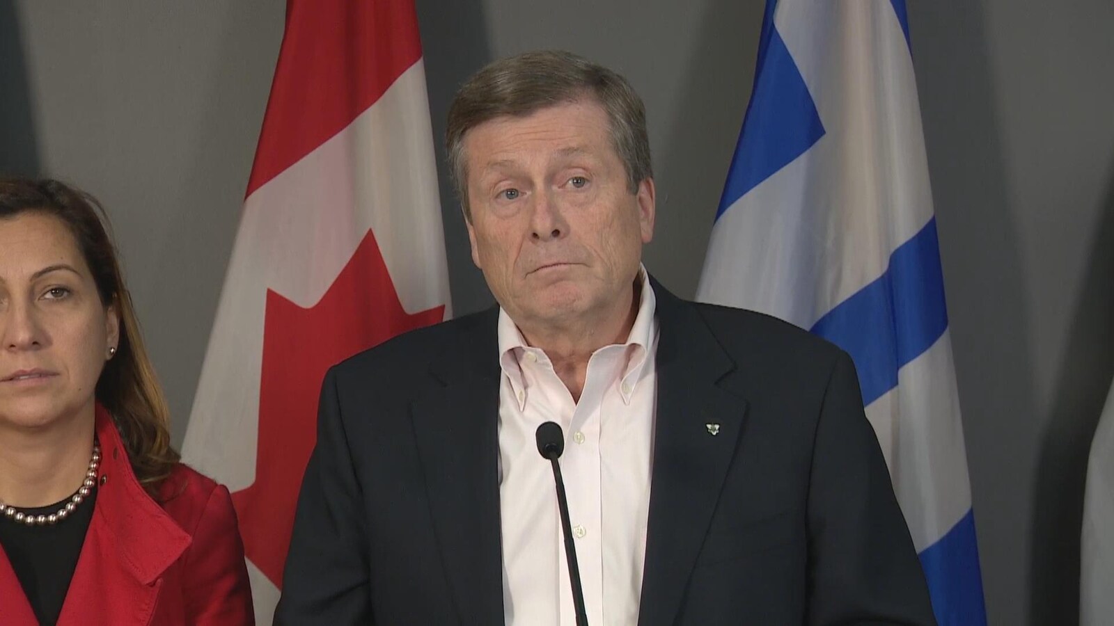 Un homme en veston devant des drapeaux