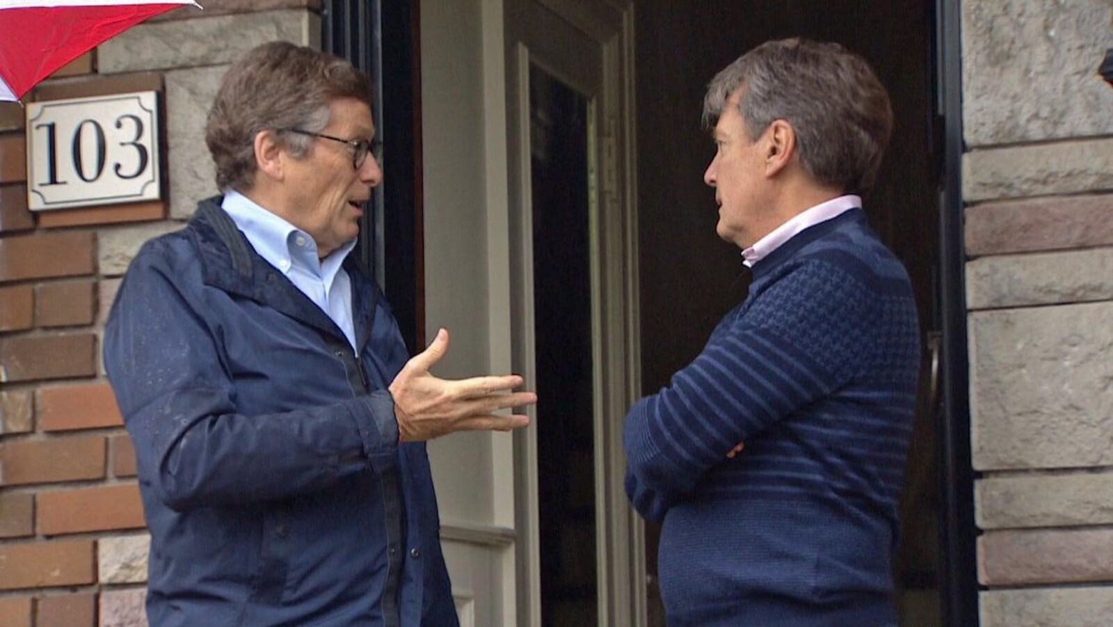 Le maire Tory avec un autre homme parle sur le perron d'une maison.
