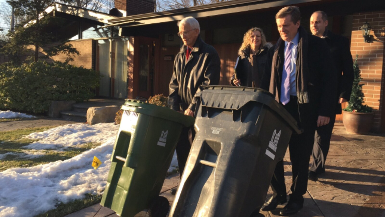 Photo de John Tory qui fait rouler une poubelle jusqu'au bord de la rue.