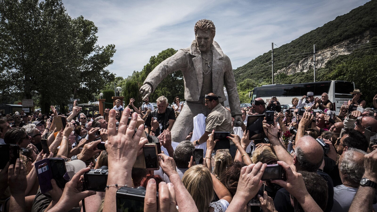 Une foule de fans de Johnny Hallyday prennent des photos alors qu'ils entourent la statue de 3 mètres érigée en son honneur.