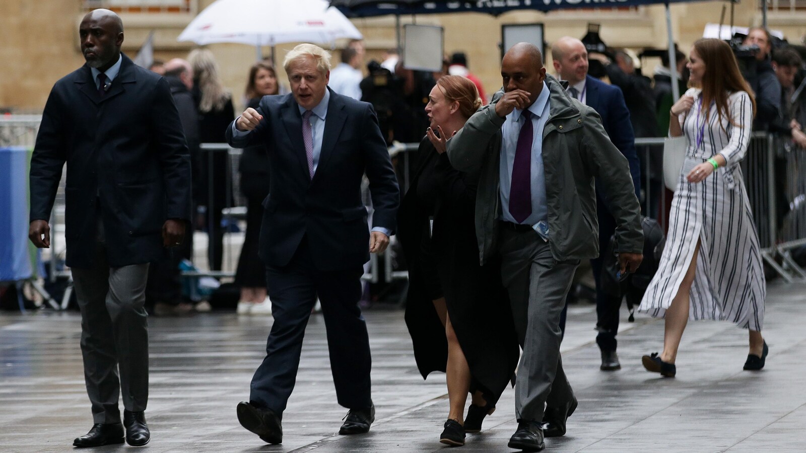 Boris Johnson avance avec le bras droit levé.