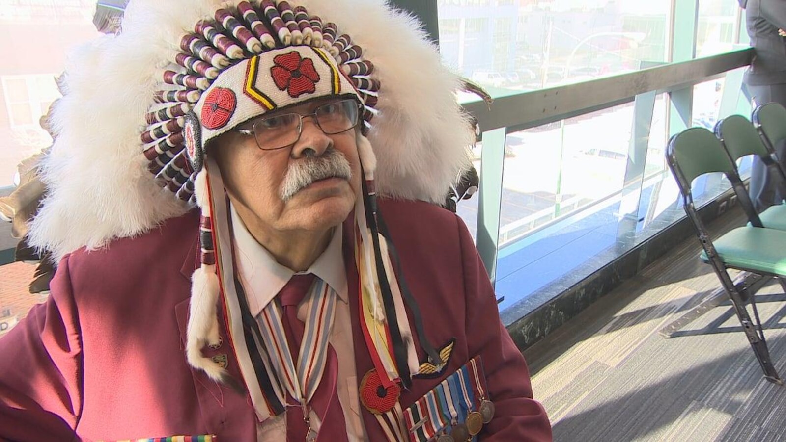 Joseph Meconse porte une coiffure de plumes et des médailles des Forces armées canadiennes.