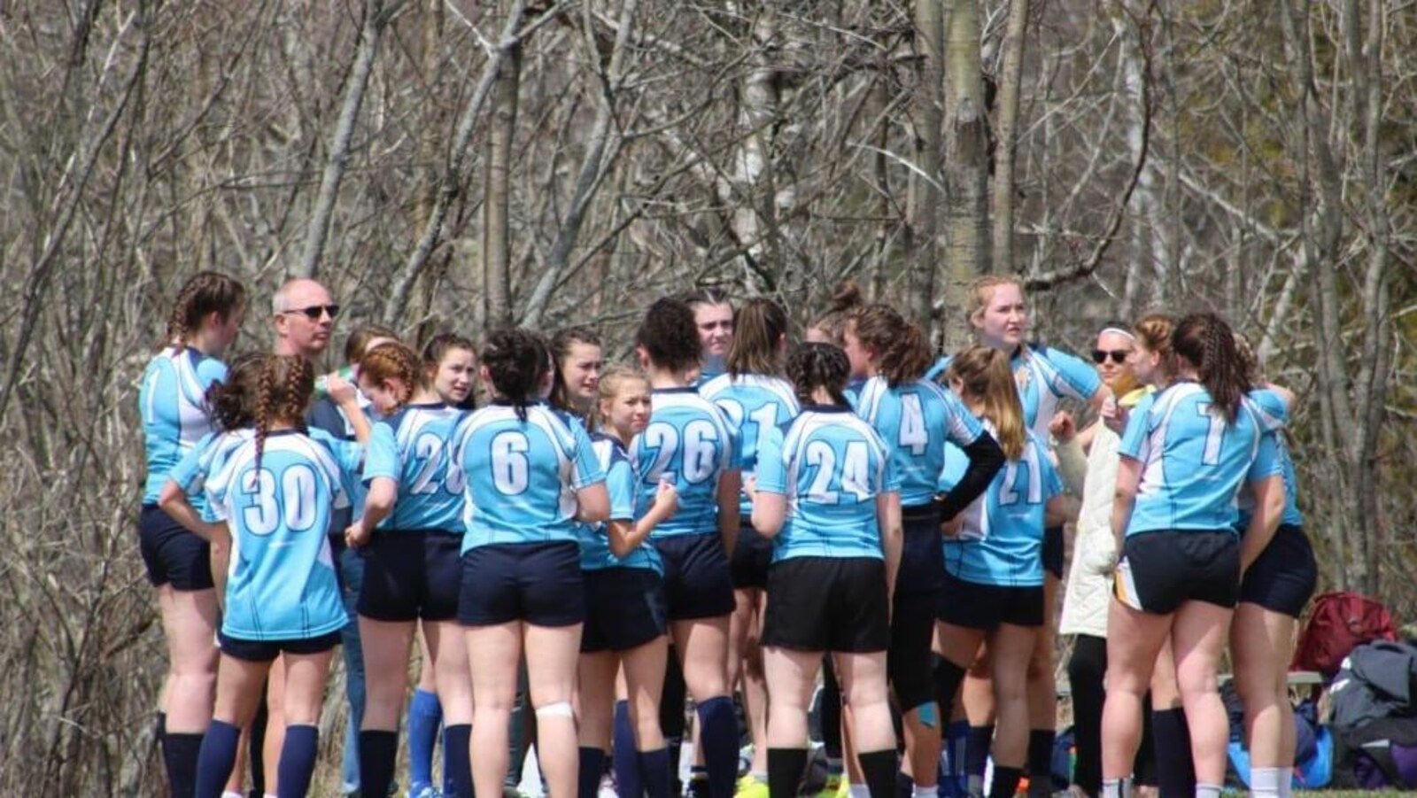 Des joueuses de rugby se concertent sur un terrain.