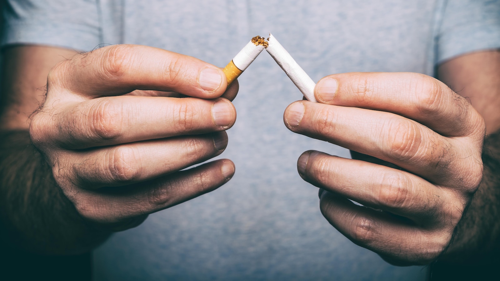 Des mains masculines brisent une cigarette.