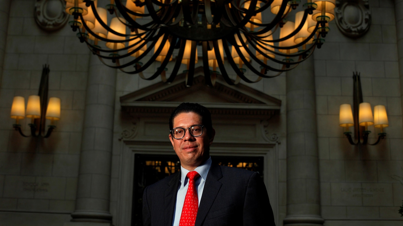 Un négociateur mexicain debout devant un immeuble imposant doté de colonnes et de lustres.