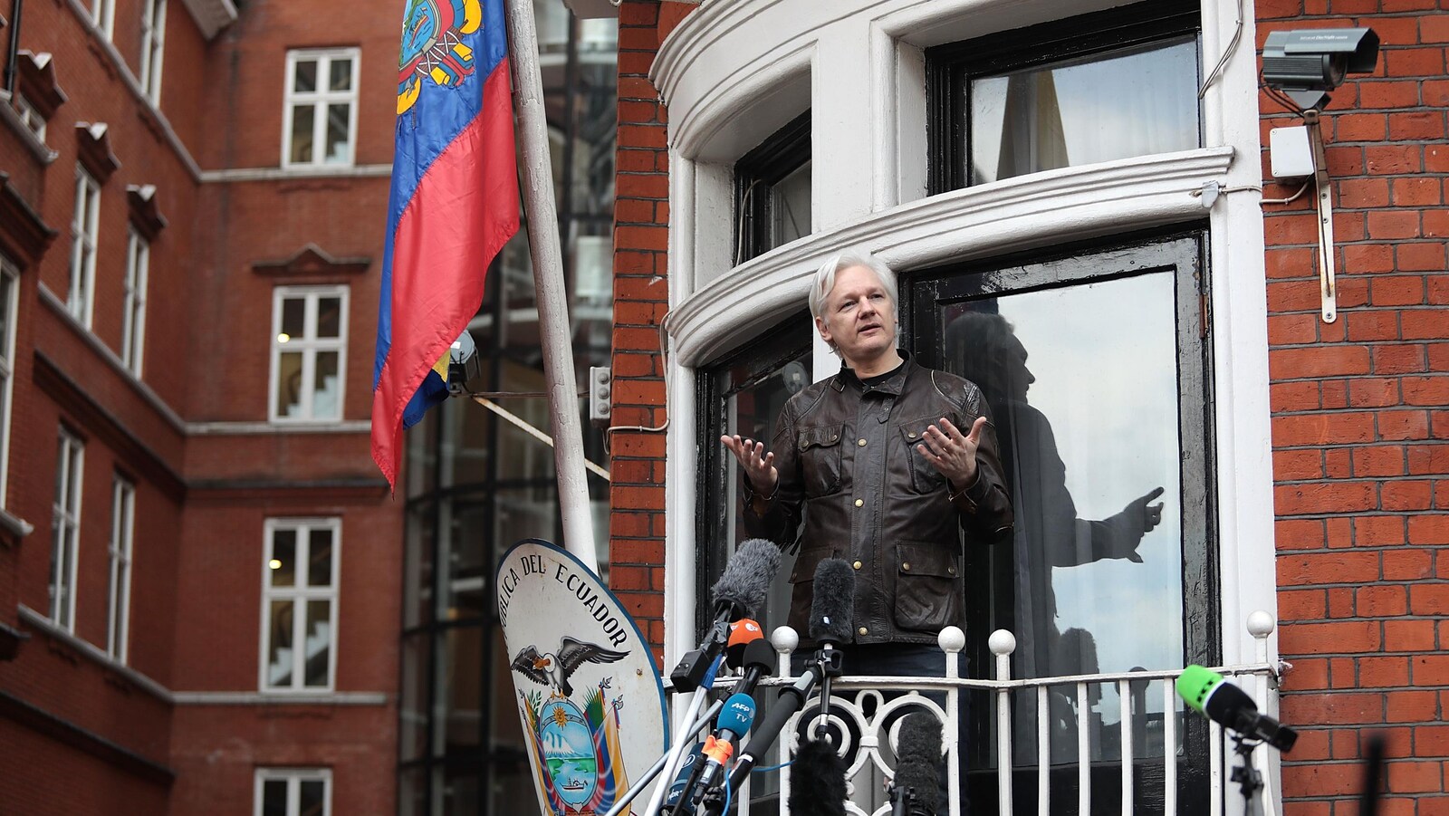 Julien Assange au balcon de l'ambassade équatorienne à Londres, devant des micros placés au bout de perches.