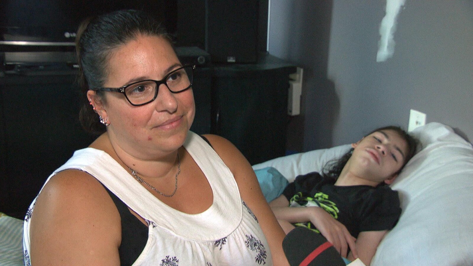 Julie-Anne Perron répond aux questions d'une journaliste. Son fils, Justin, est dans un lit en arrière plan.