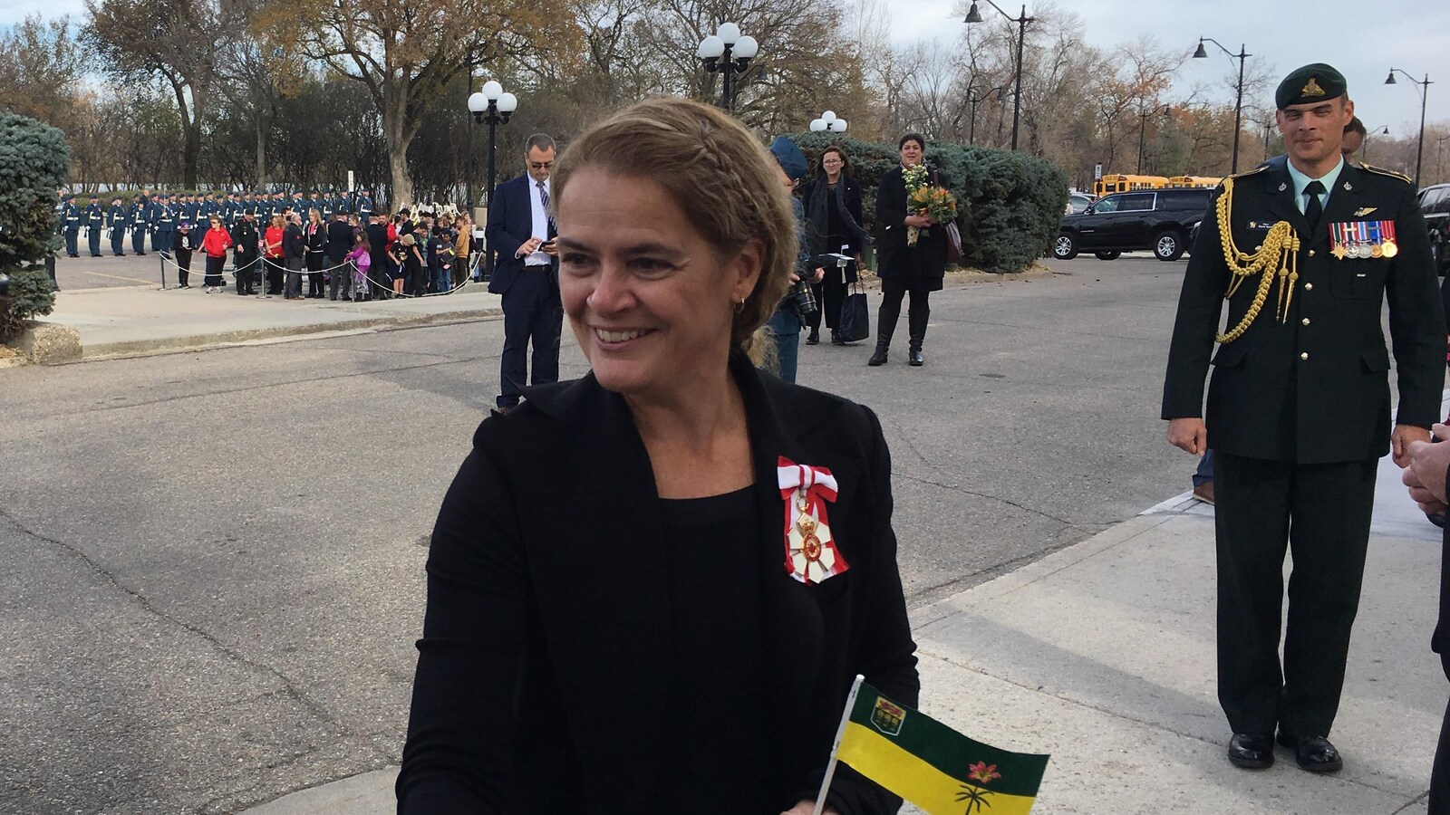 Julie Payette sert la main d'une femme en tenant dans l'autre main un drapeau de la Saskatchewan.