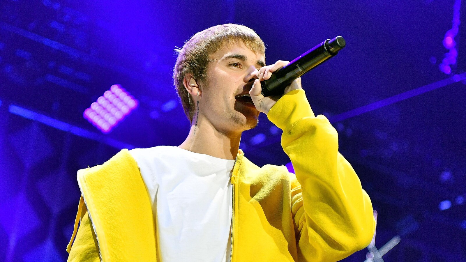Justin Bieber, microphone à la main, chante sur scène lors d'un concert.