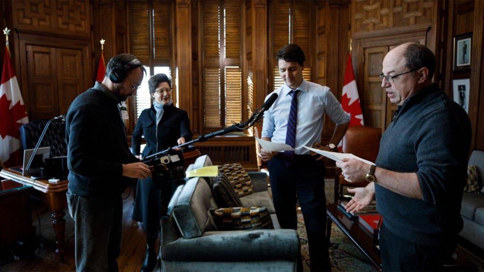 Le premier ministre Justin Trudeau qui lit un script, dans son bureau, avec des techniciens de son équipés d'une perche de microphone, et le créateur de <em>Corner Gas</em>, Brent Butt (à droite).