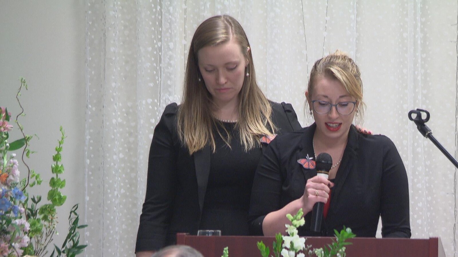 À gauche, Holly met sa main sur l'épaule de sa soeur Karen pendant que cette dernière rend hommage à leur mère.