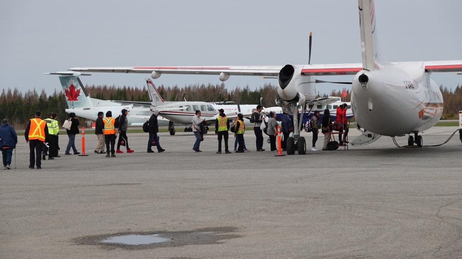Des gens sur le tarmac qui montent à bord d’un avion.