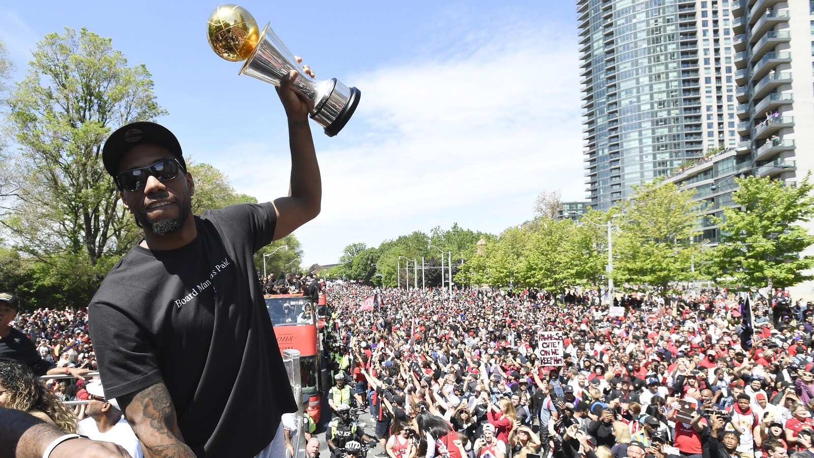 Un joueur montre un trophée à la foule qui remplit complètement la rue.