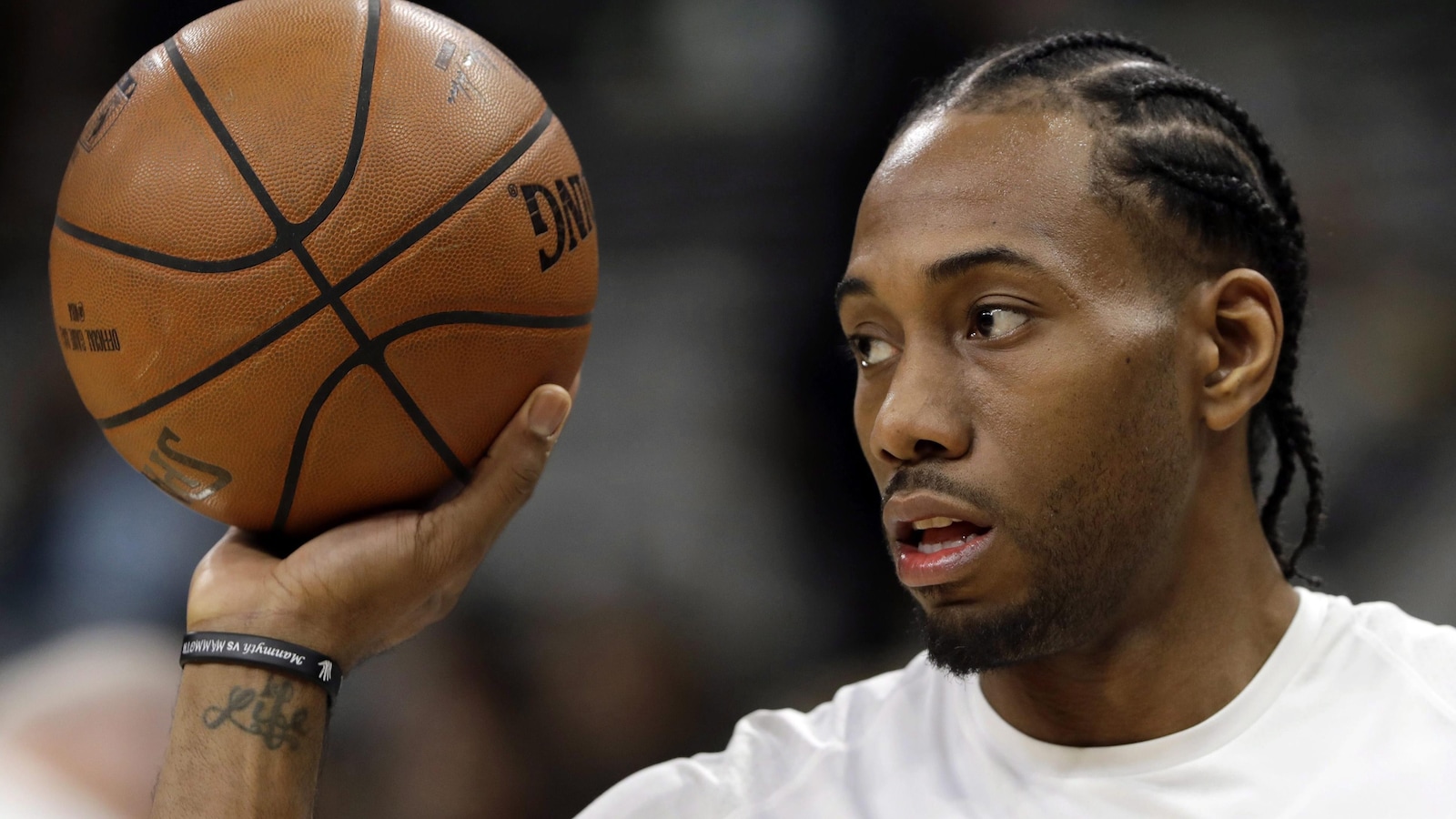 Un jeune homme noir tient un ballon de basketball dans la main.