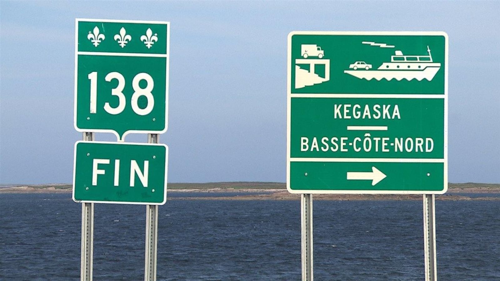 Un panneau annonçant la fin de la route 138 à côté d'un panneau annonçant la traverse Kegaska-Basse-Côte-Nord.