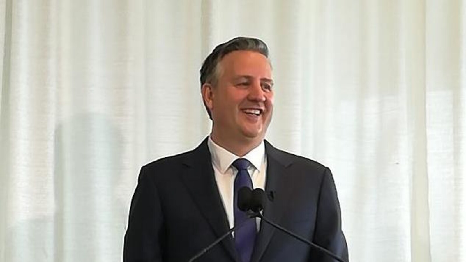 Un homme fait une annonce derrière un podium.