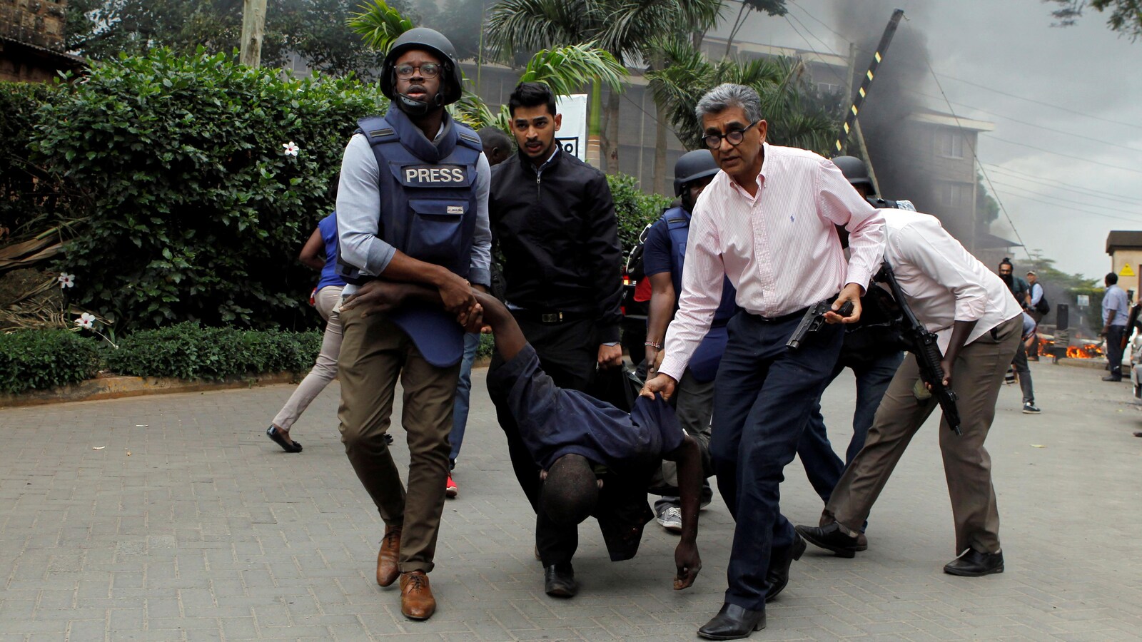 Des sauveteurs et des journalistes évacuent un homme blessé des lieux où des explosions et des coups de feu ont été entendus à l'hôtel Dusit, à Nairobi.