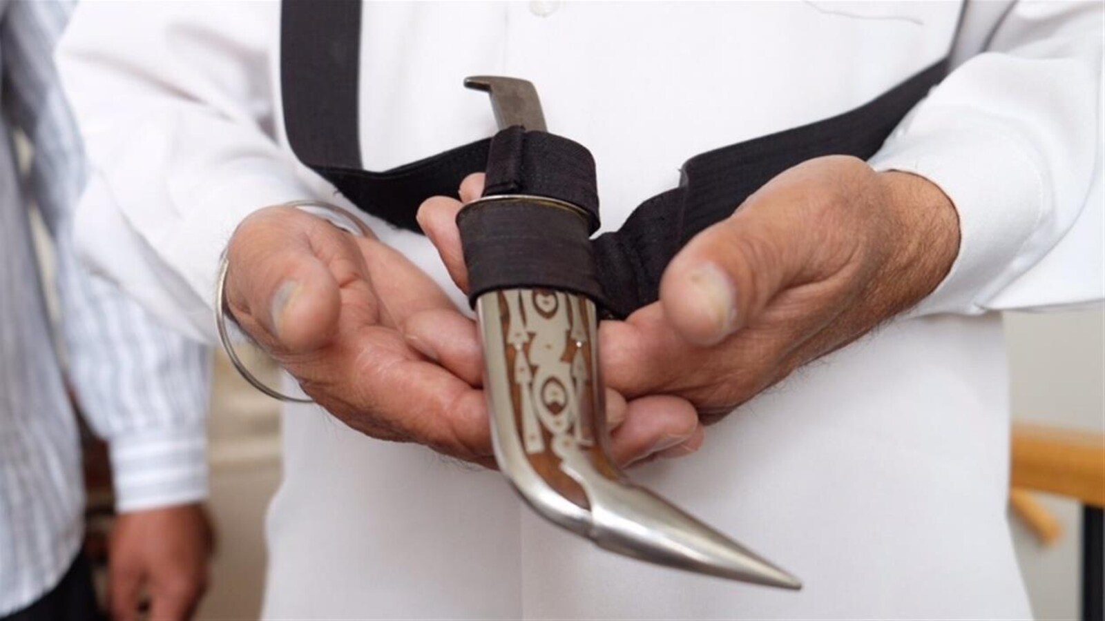 Un homme tient un kirpan dans ses mains.