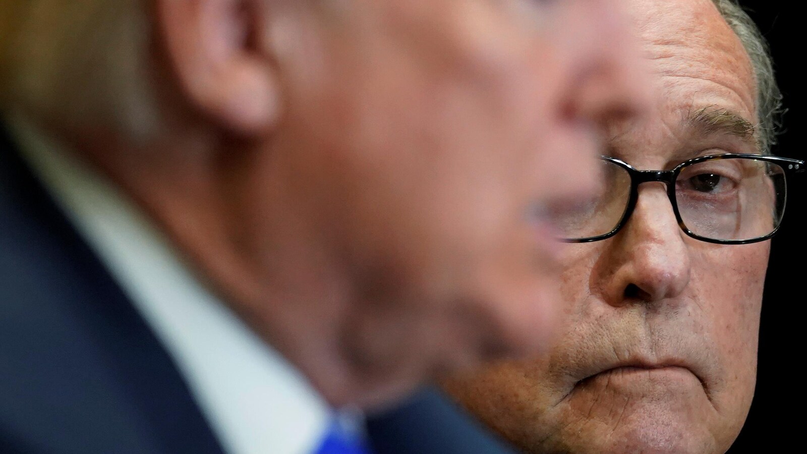 Larry Kudlow avec, devant lui, le visage flou de Donald Trump.