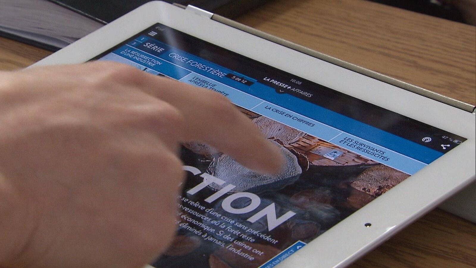 Un doigt fait défiler le contenu de La Presse sur une tablette.