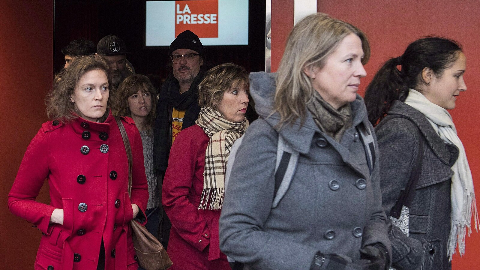 Des gens sortent d'une salle.