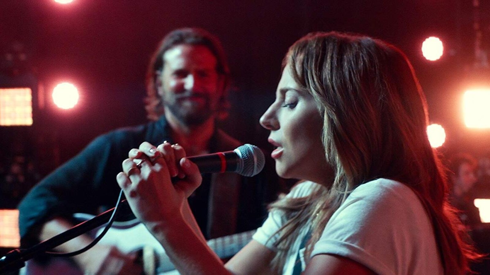 Bradley Cooper, qui joue de la guitare, et Lady Gaga, qui chante au micro, dans le film A Star Is Born.
