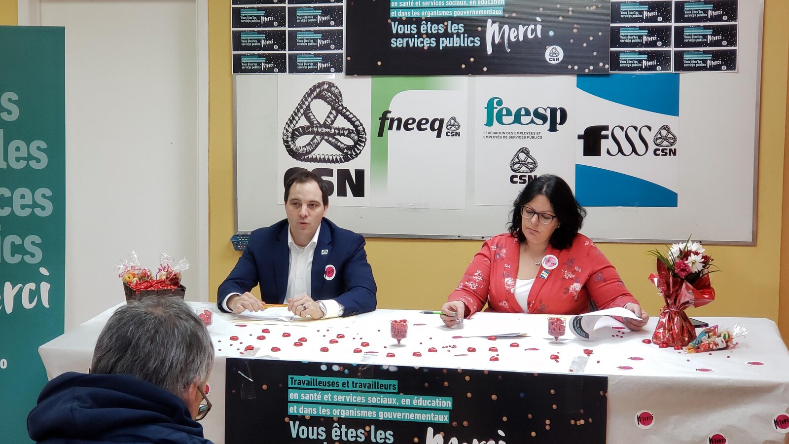 Un homme et une femme sont assis derrière une table lors d'une conférence de presse de la CSN.