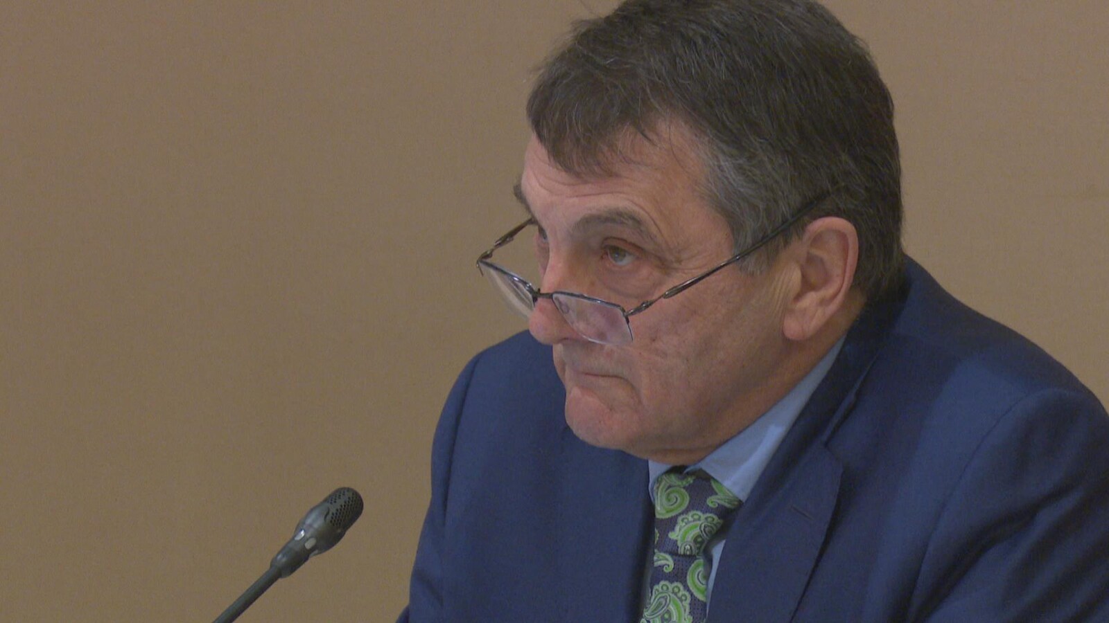 Un homme en complet répond à des questions au micro.