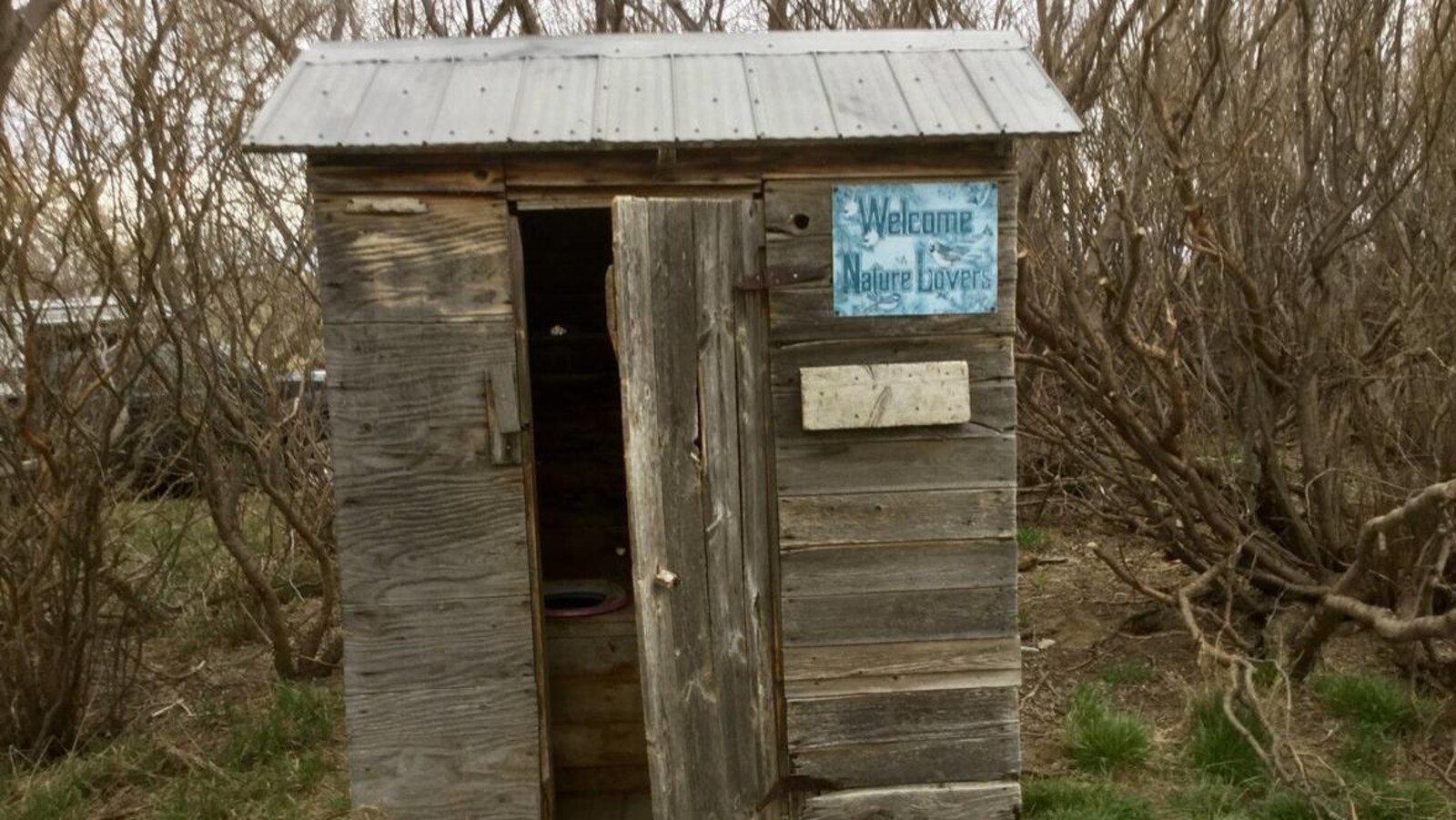Une latrine en bois dans un bosquet.