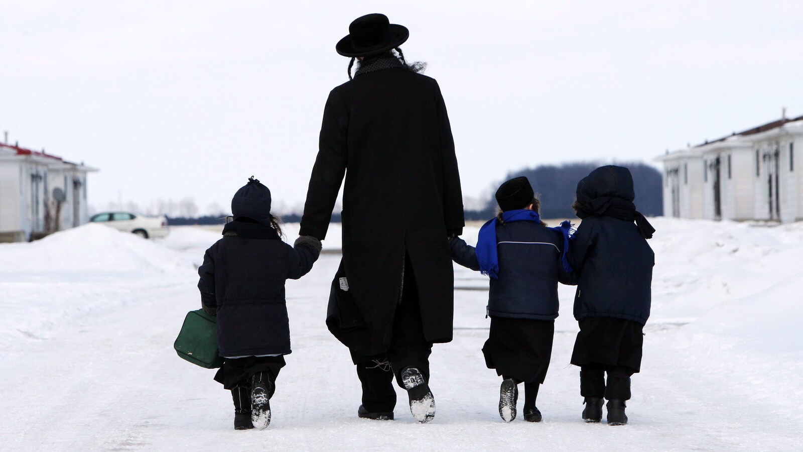 Un homme tient des enfants par la main.