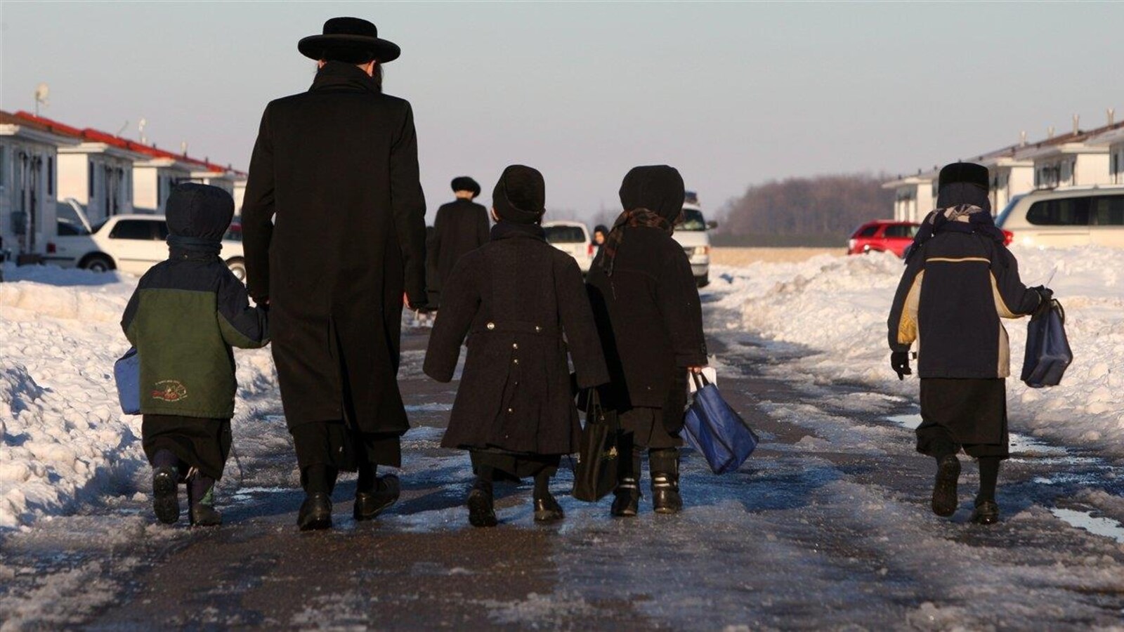 Des enfants et un adulte membres de la secte Lev Tahor marchent dans la neige.