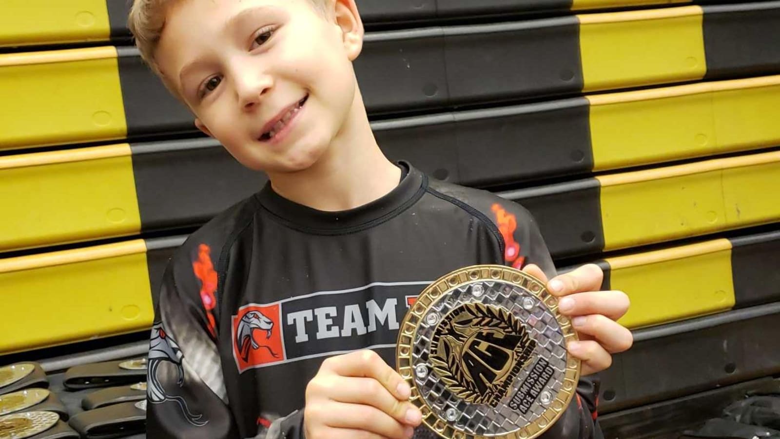 Une jeune garçon tient une médaille dans ses mains.