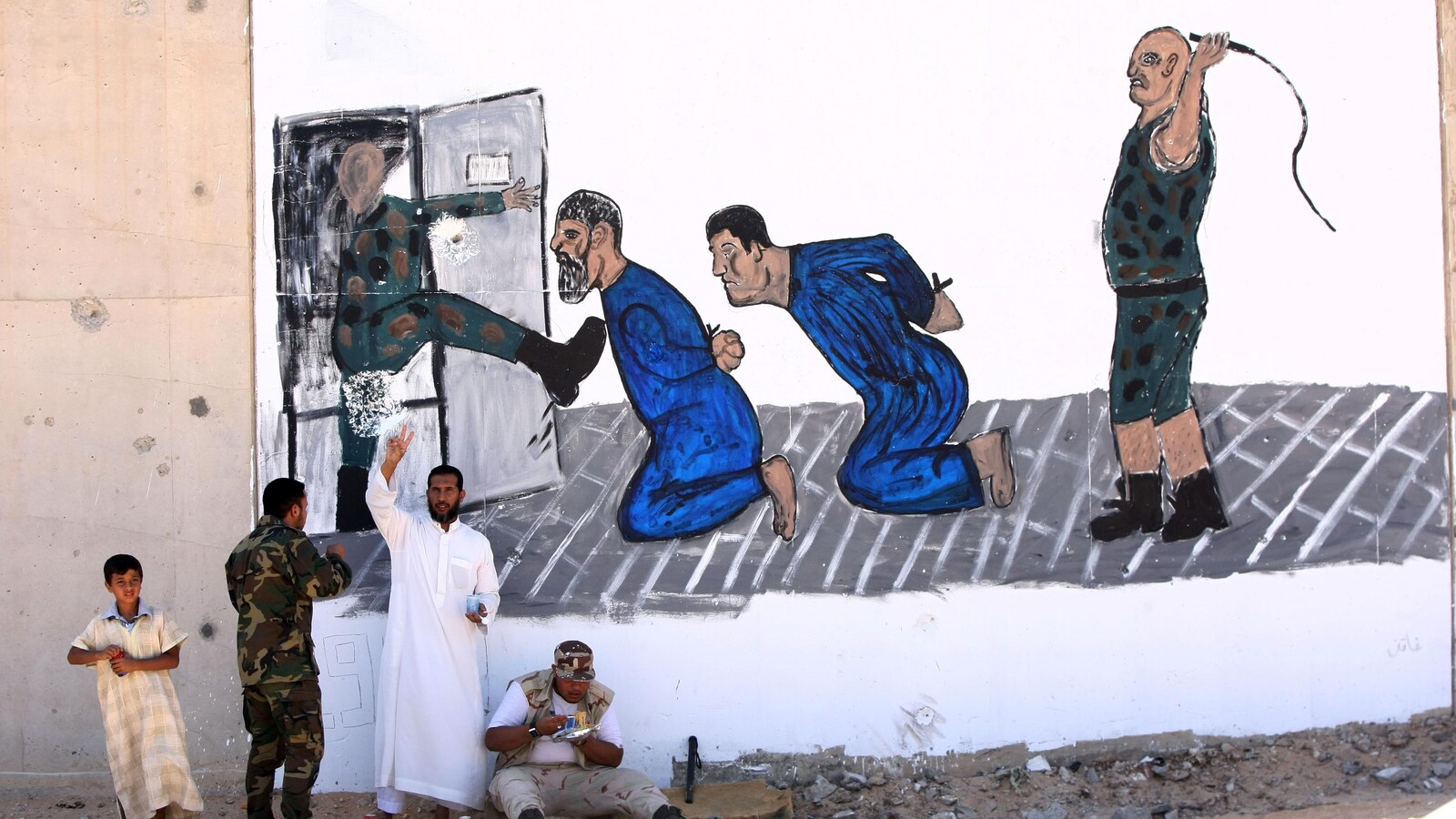 Des Libyens, devant une murale commémorant un massacre de prisonniers survenu à la prison d'Abou Slim.