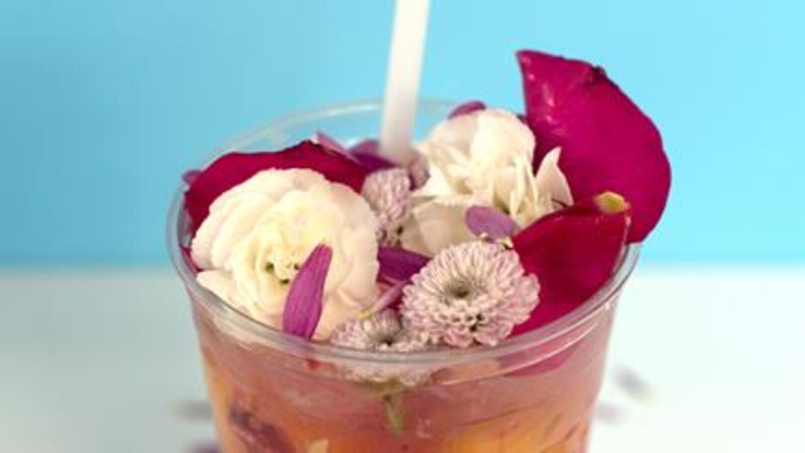 Une limonade avec des fleurs comestibles dans un verre en plastique.