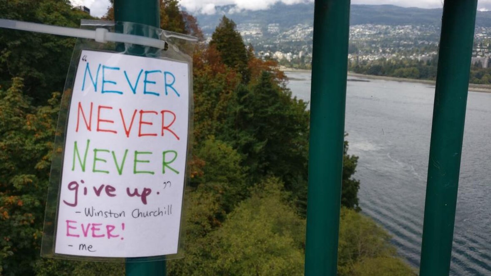 Un message écrit à la main où on peut lire Never, never, never give up, ever. installé sur le pont Lions Gate.