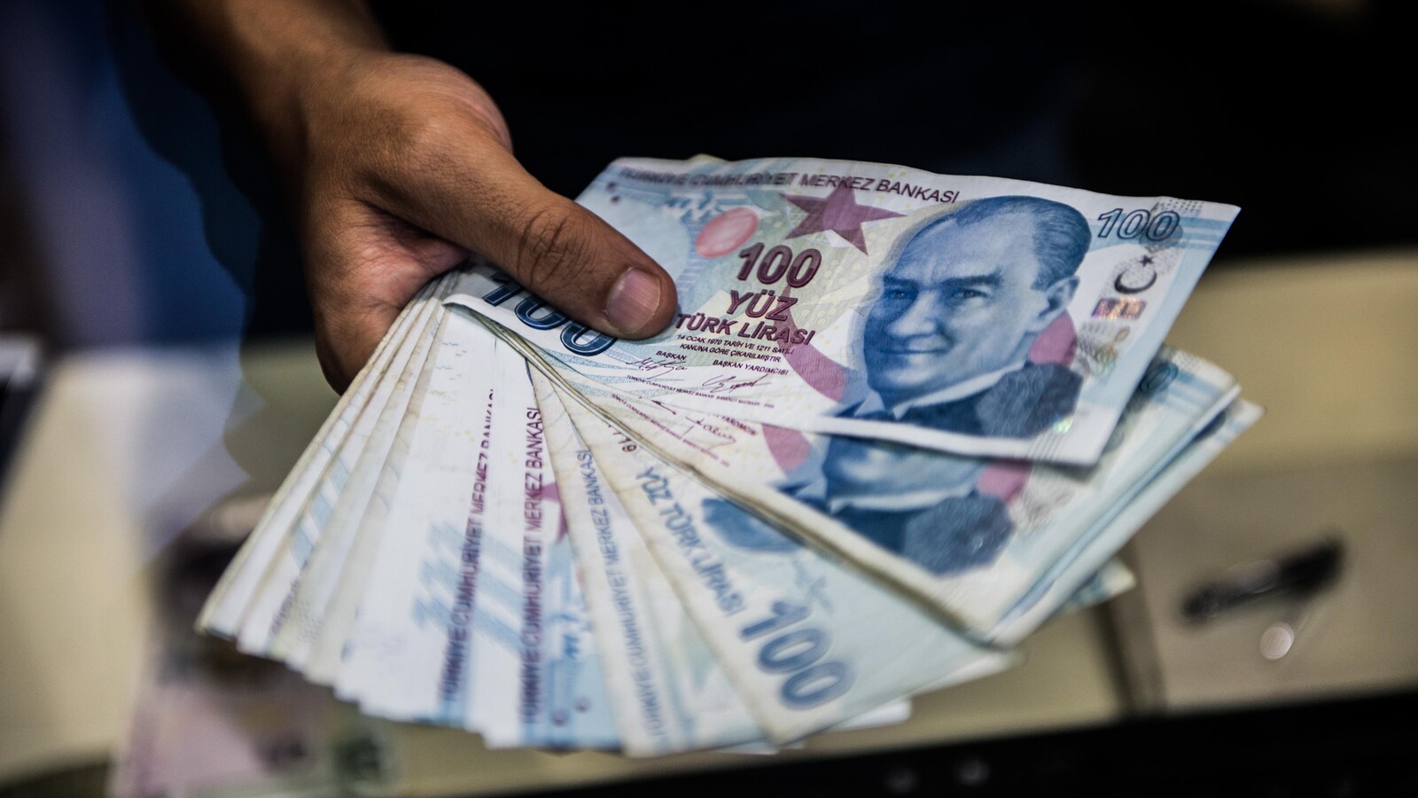 Un homme tient dans sa main des billets de 100 livres turques.