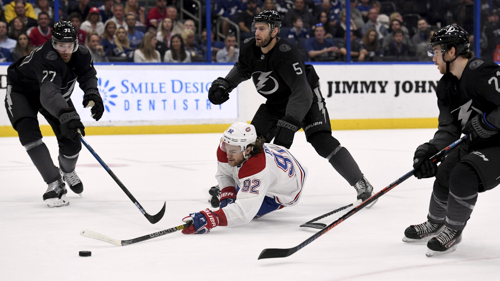 Entouré de trois joueurs du Lightning, Jonathan Drouin tombe au sol en perdant le contrôle de la rondelle.
