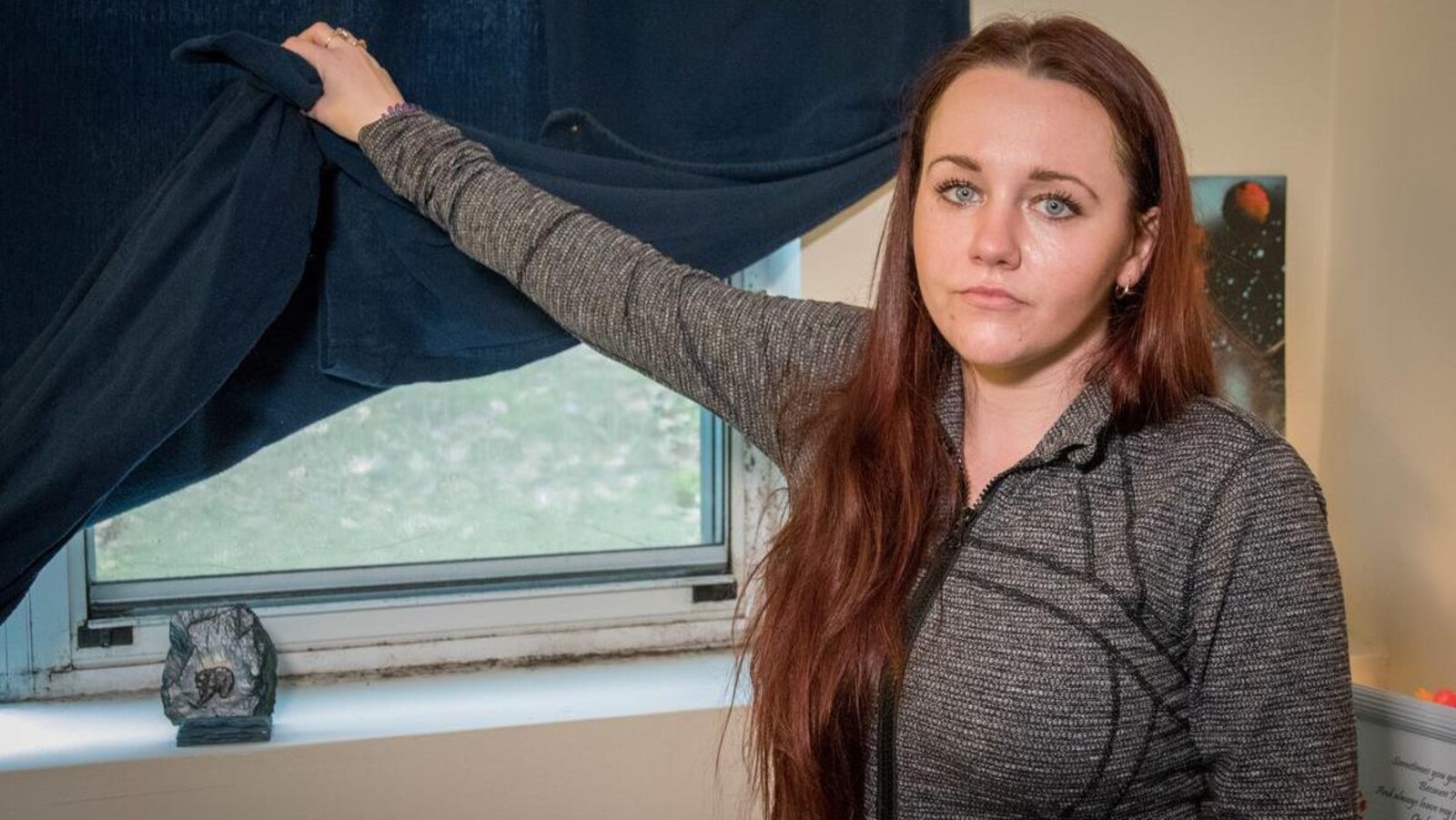 Karlee Kedy ouvre un rideau pour montrer les moisissures sur le rebord de sa fenêtre.