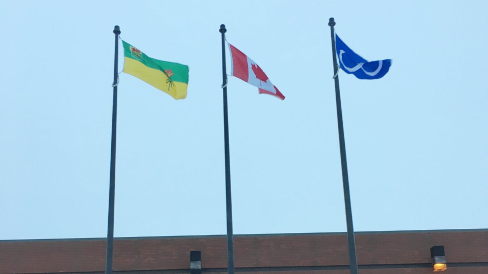 Trois drapeaux en plein coeur devant le quartier général de la GRC en hommage à Louis Riel.