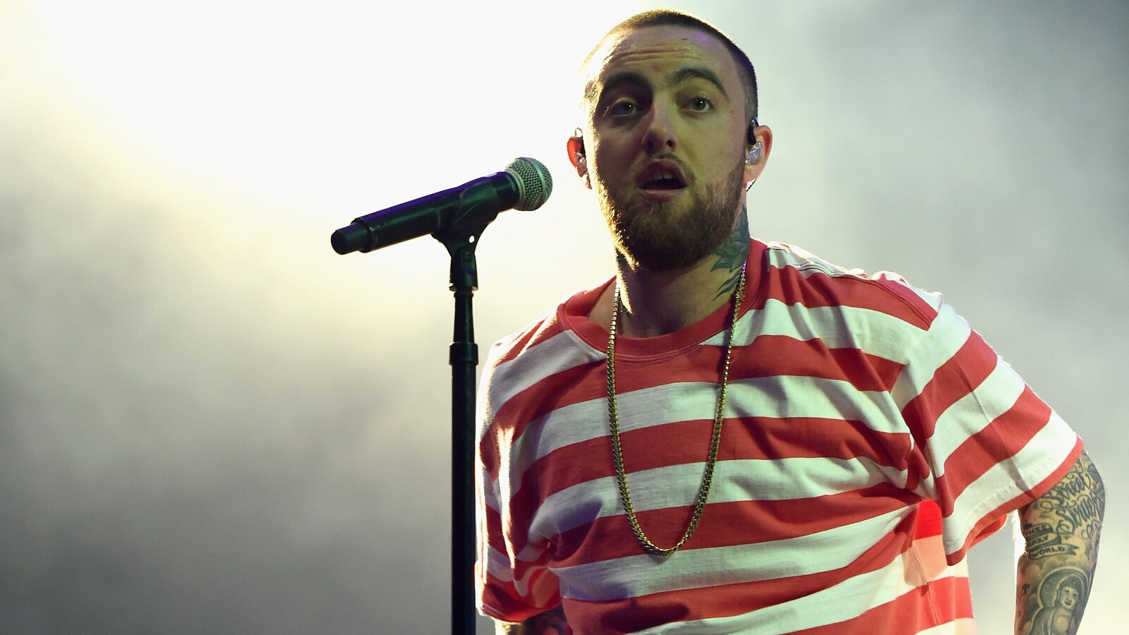 Le rappeur Mac Miller semble remonter son chandail alors qu'il se tient devant un micro en concert à Los Angeles, en octobre 2017.